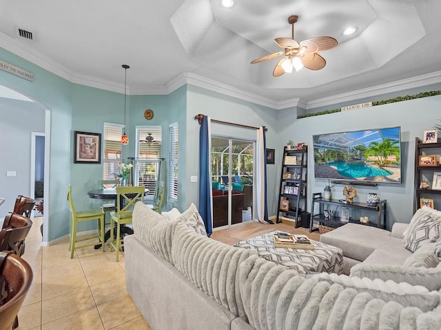 tiled living room featuring a raised ceiling, ornamental molding, and ceiling fan