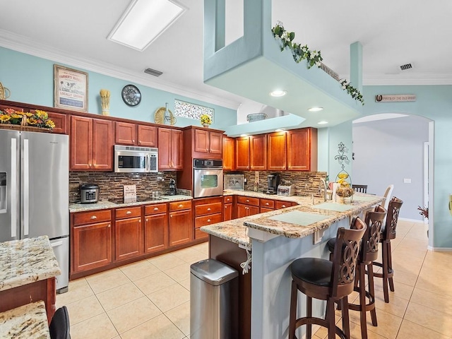 kitchen with a breakfast bar, stainless steel appliances, kitchen peninsula, and light tile patterned floors