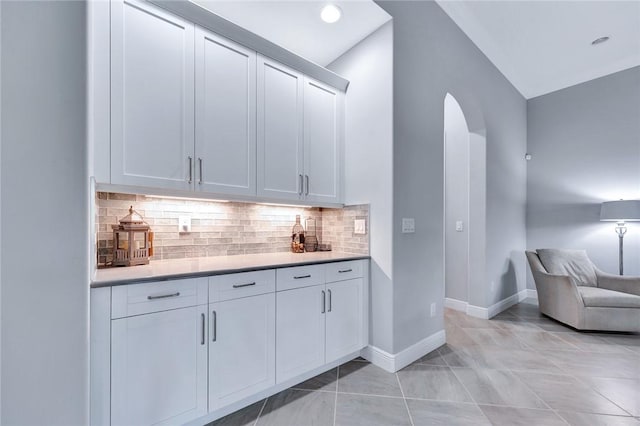 bar featuring backsplash, white cabinetry, and light tile patterned floors