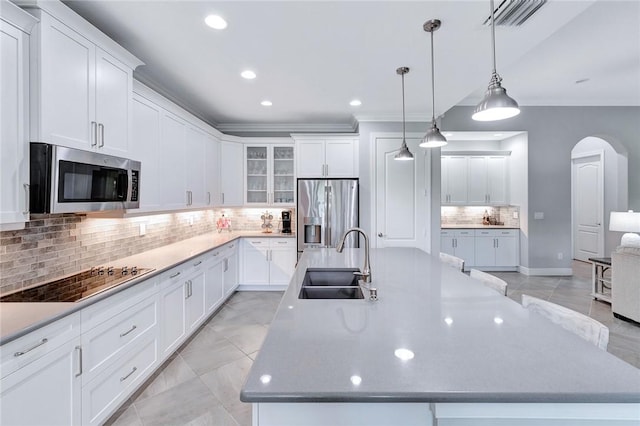 kitchen with decorative backsplash, appliances with stainless steel finishes, sink, white cabinetry, and a large island