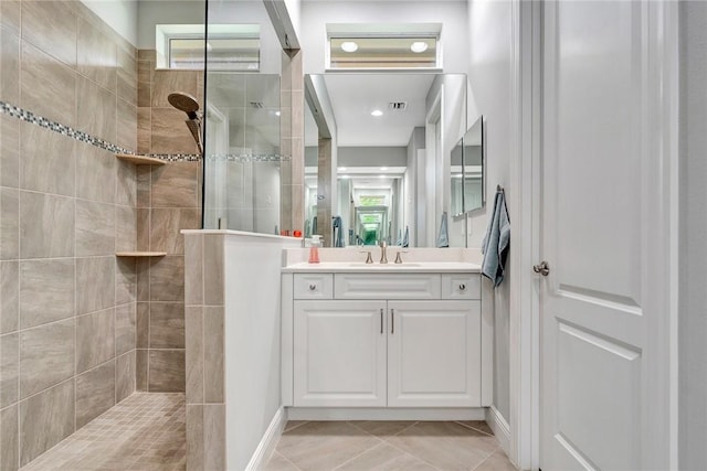 bathroom with tile patterned flooring, vanity, and tiled shower