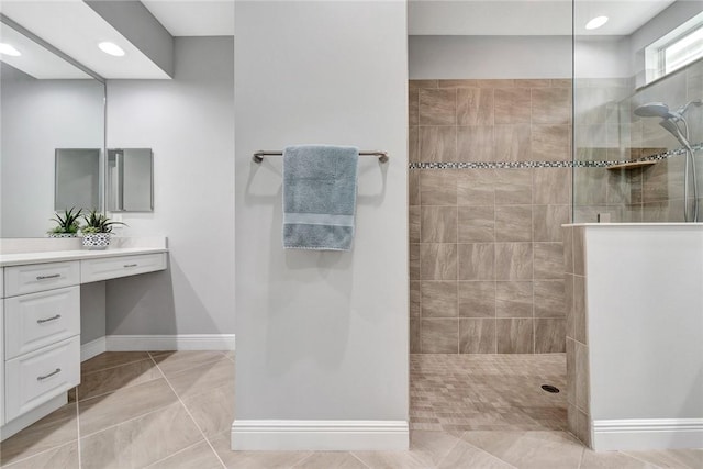 bathroom with a tile shower, tile patterned flooring, and vanity