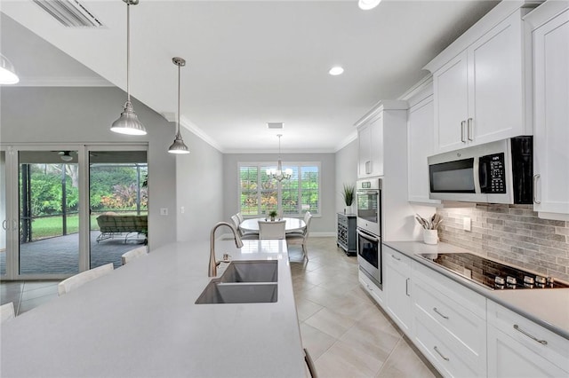 kitchen featuring pendant lighting, white cabinets, sink, ornamental molding, and stainless steel appliances