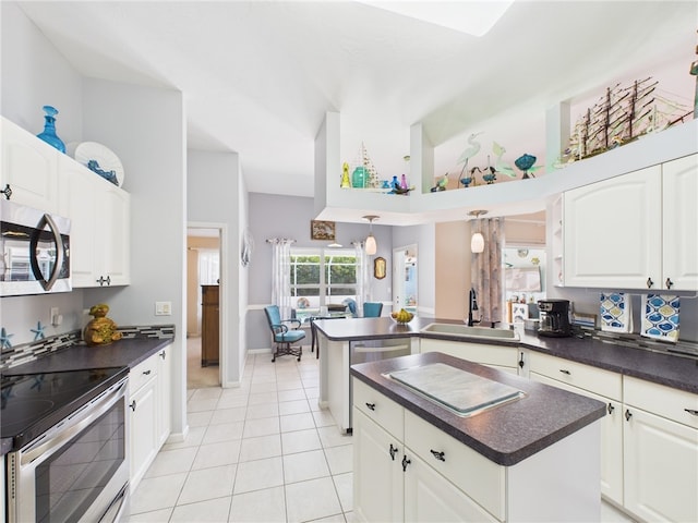 kitchen with a sink, stainless steel appliances, dark countertops, and a peninsula