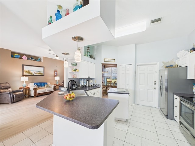 kitchen with dark countertops, visible vents, a kitchen island, stainless steel appliances, and a sink