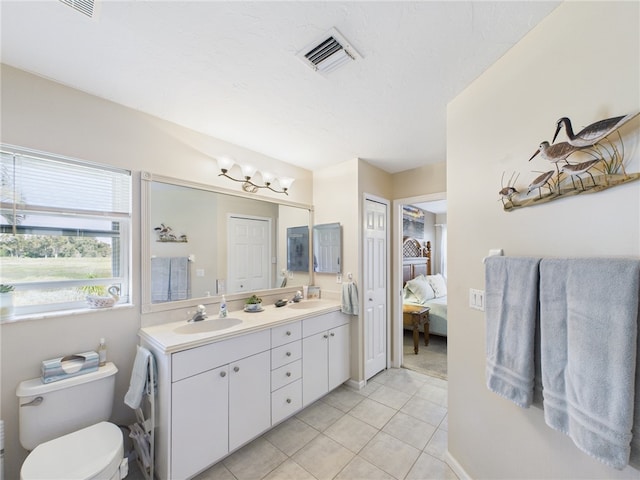 full bathroom with visible vents, double vanity, a sink, tile patterned flooring, and toilet