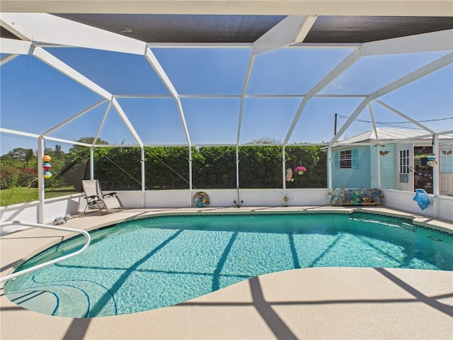 outdoor pool featuring glass enclosure and a patio area