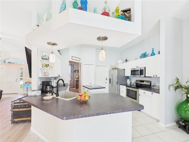 kitchen featuring dark countertops, appliances with stainless steel finishes, a towering ceiling, and a sink