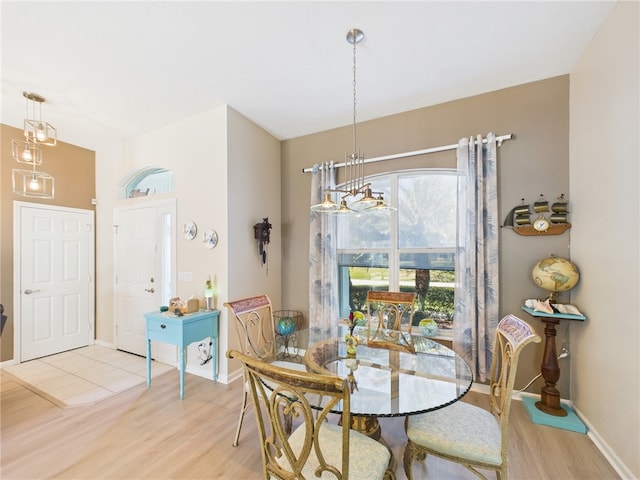 dining room with baseboards, an inviting chandelier, and light wood finished floors