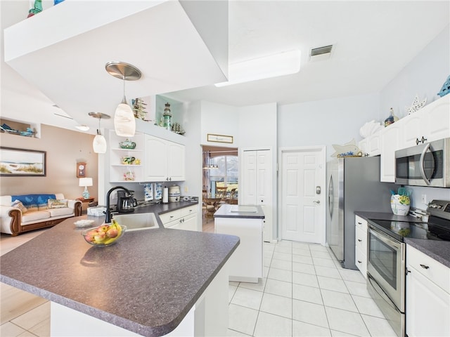 kitchen with visible vents, a kitchen island, a sink, appliances with stainless steel finishes, and dark countertops