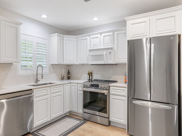 kitchen with light hardwood / wood-style floors, white cabinetry, sink, and appliances with stainless steel finishes