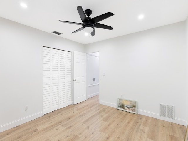 unfurnished bedroom with light wood-type flooring, ceiling fan, and a closet