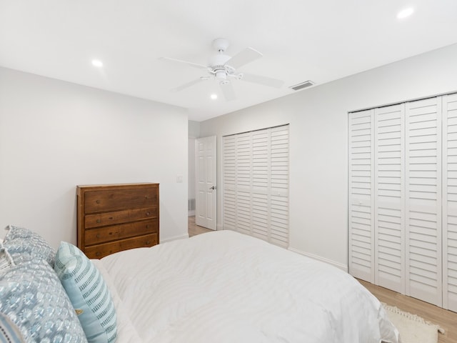 bedroom featuring light hardwood / wood-style flooring, ceiling fan, and two closets