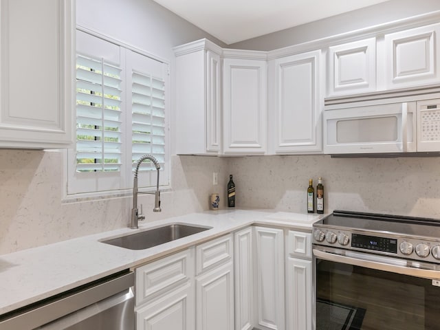 kitchen featuring white cabinetry, appliances with stainless steel finishes, sink, and light stone countertops