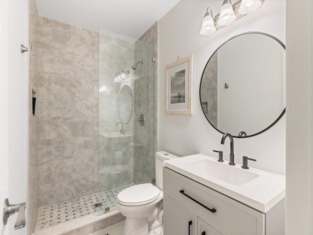 bathroom with toilet, vanity, and a tile shower