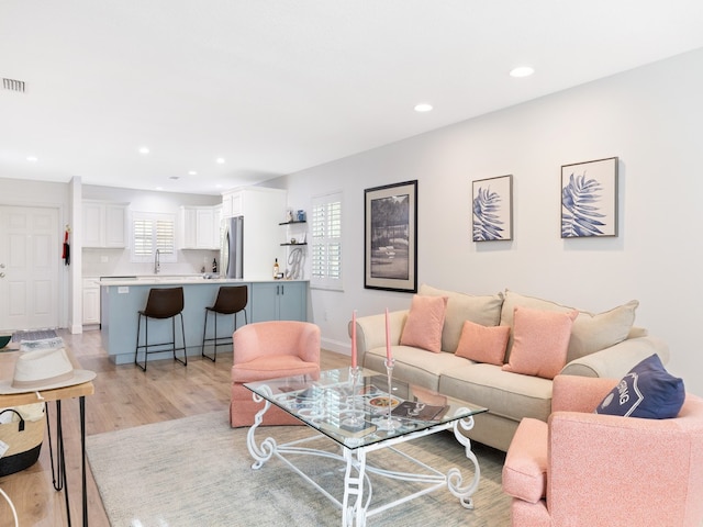 living room featuring sink, a healthy amount of sunlight, and light hardwood / wood-style flooring