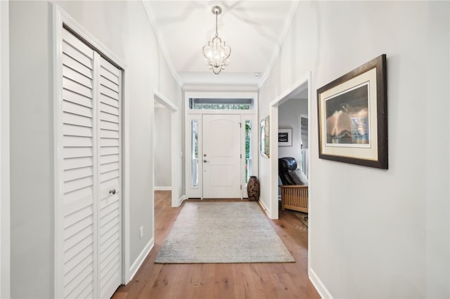 foyer featuring hardwood / wood-style floors, ornamental molding, and a notable chandelier