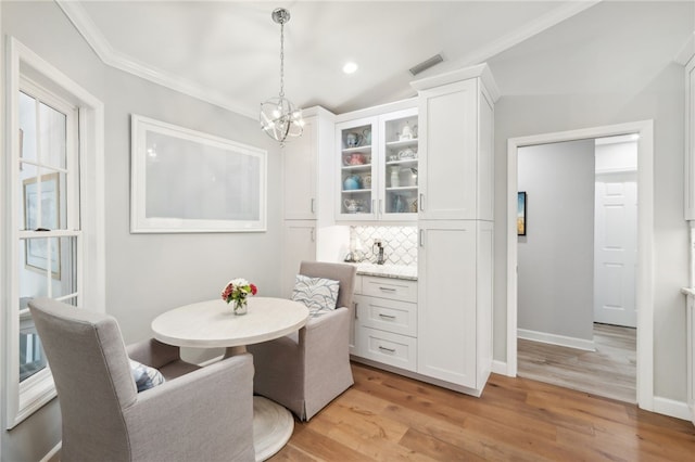 dining area featuring light hardwood / wood-style floors, lofted ceiling, crown molding, and a chandelier