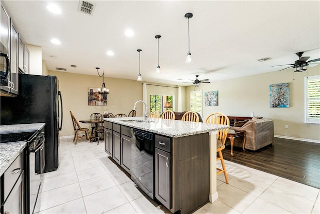 kitchen featuring black appliances, a kitchen breakfast bar, visible vents, and a sink