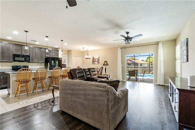 living room with baseboards, ceiling fan, recessed lighting, wood finished floors, and a textured ceiling