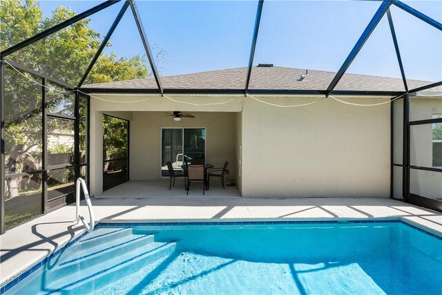 pool with glass enclosure, a ceiling fan, and a patio area