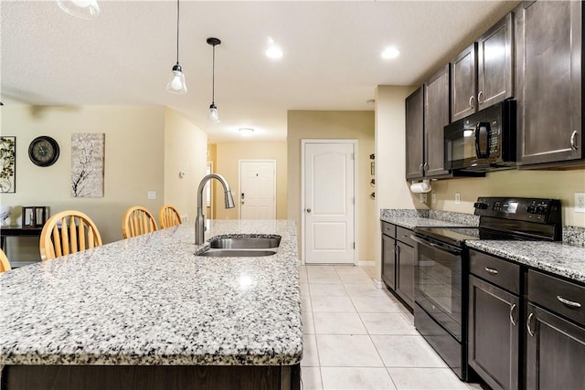 kitchen featuring black appliances, a kitchen island with sink, a sink, light tile patterned floors, and dark brown cabinets