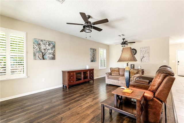 living room with a ceiling fan, baseboards, wood finished floors, visible vents, and a textured ceiling