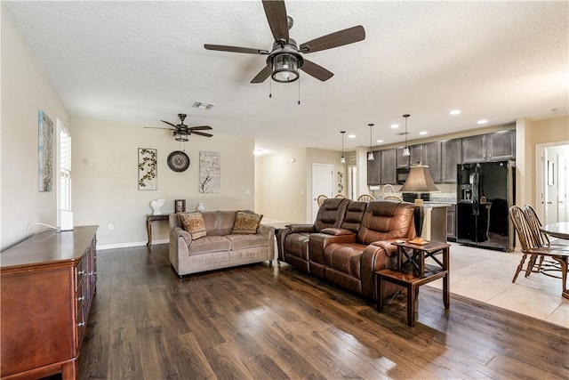 living area with visible vents, dark wood-type flooring, a textured ceiling, recessed lighting, and baseboards