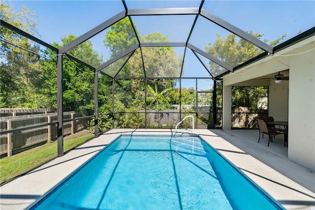 outdoor pool featuring a patio area, glass enclosure, a ceiling fan, and fence