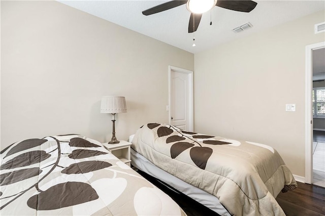 bedroom with baseboards, wood finished floors, visible vents, and ceiling fan