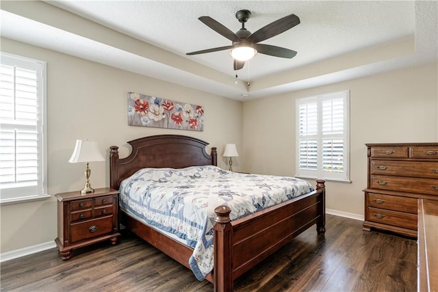 bedroom featuring dark wood-type flooring, baseboards, and a tray ceiling