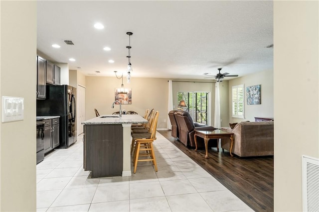 kitchen featuring a sink, visible vents, a breakfast bar, and open floor plan