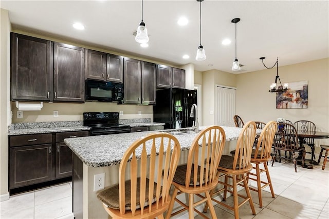 kitchen with a center island with sink, a breakfast bar area, light tile patterned floors, recessed lighting, and black appliances