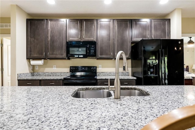 kitchen featuring visible vents, black appliances, a sink, light stone countertops, and dark brown cabinets