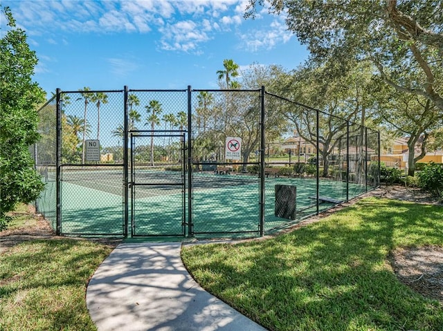 view of tennis court featuring a gate, fence, and a yard
