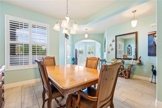dining room featuring arched walkways, a notable chandelier, and baseboards