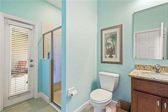 bathroom with baseboards, vanity, a shower stall, and toilet