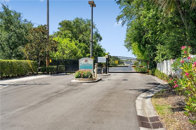 view of street featuring a gate, a gated entry, and curbs