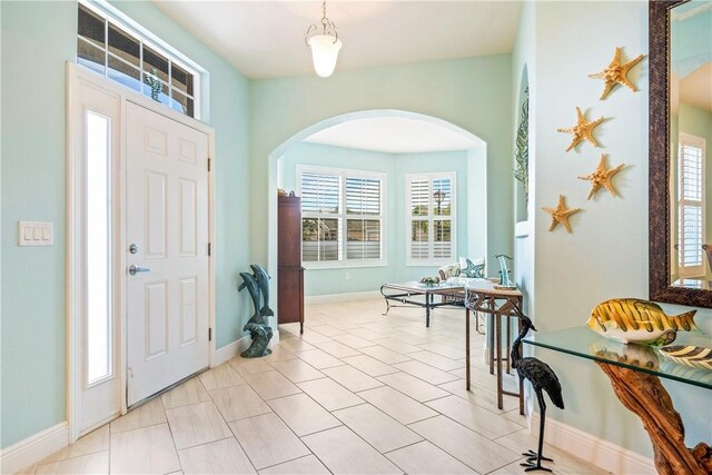 foyer featuring arched walkways and baseboards