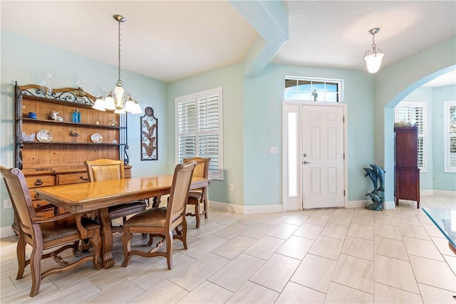 dining room featuring arched walkways, baseboards, and an inviting chandelier