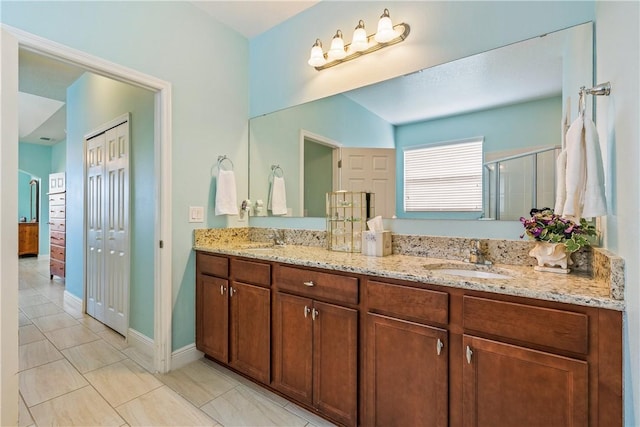 full bath with a shower stall, tile patterned floors, a sink, and double vanity