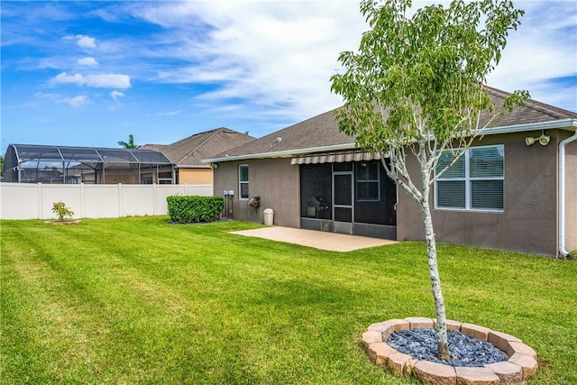 rear view of property featuring a lawn, fence, a patio, stucco siding, and a sunroom