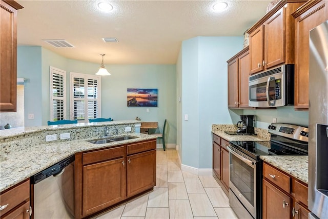 kitchen featuring stainless steel appliances, a sink, visible vents, brown cabinets, and light stone countertops