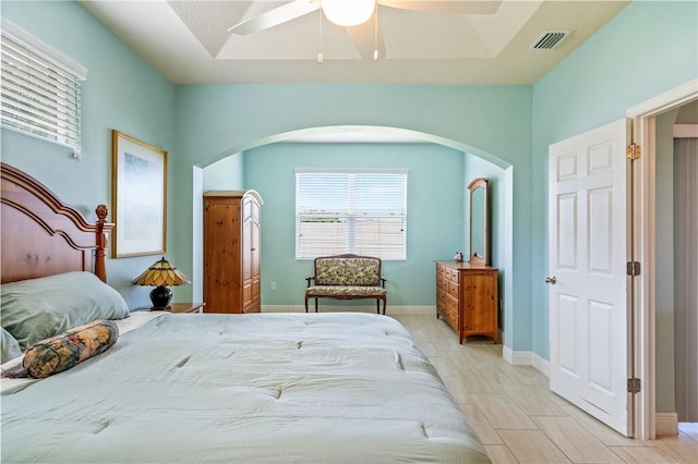 bedroom featuring arched walkways, a ceiling fan, visible vents, and baseboards