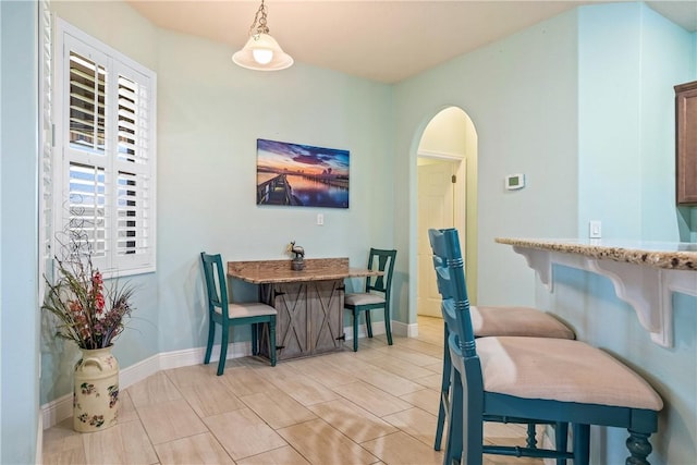 dining room featuring arched walkways and baseboards