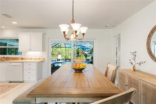 dining area featuring a notable chandelier, sink, and light hardwood / wood-style flooring