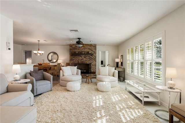 living room featuring ceiling fan with notable chandelier and a brick fireplace