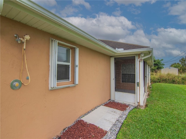 entrance to property featuring stucco siding and a yard