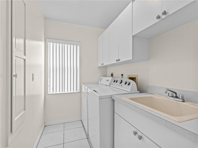 washroom featuring a sink, cabinet space, light tile patterned floors, baseboards, and washing machine and clothes dryer