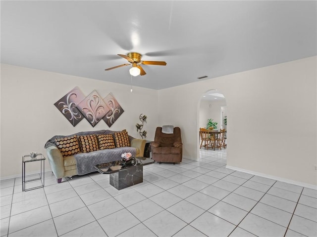 living area with visible vents, baseboards, ceiling fan, light tile patterned flooring, and arched walkways